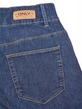 Achterkant van een blauwe spijkerbroek met het bruine ONLY "Blue Denim, anno 1995" label.