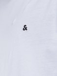 Detail van een wit T-shirt met een geborduurd zwart '&' logo op de borst.
