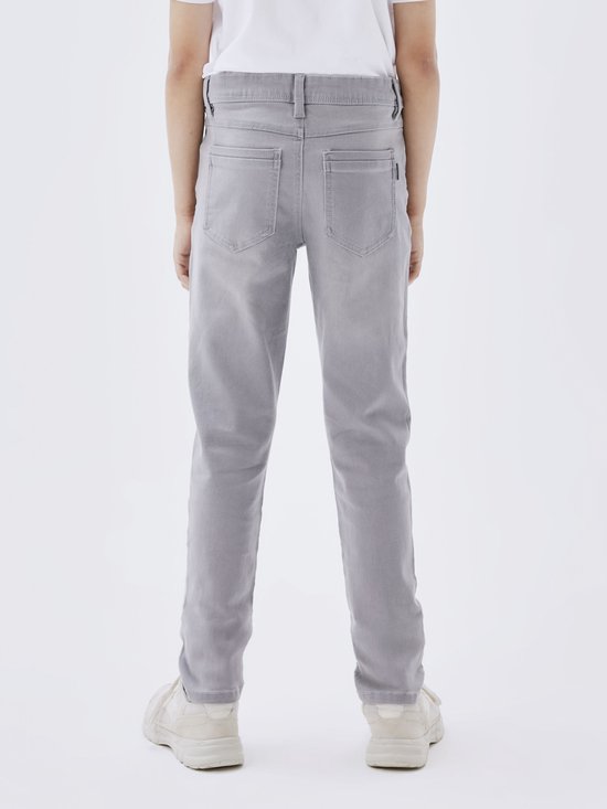 Achterkant van een grijze, aansluitende jeans met opgestikte achterzakken en zwarte stiksels.