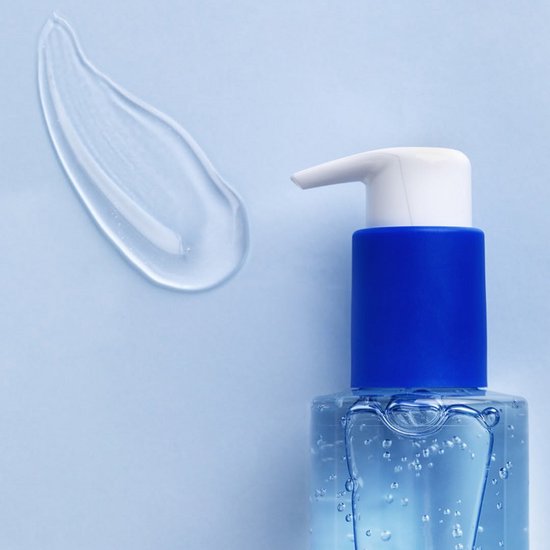 Close-up van een fles Biodermal Sensitive Balance Micellair Reinigingsgel met een witte pomp en blauwe dop, naast een veeg gel op een lichtblauwe achtergrond.