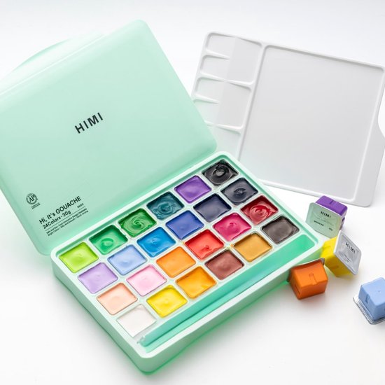 Een lichtgroene, open gouache verfdoos met 24 kleuren, een wit schilderpalet en losse oranje, gele, paarse en blauwe verfbekers.