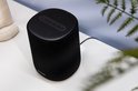 Zwarte Harman Kardon speaker met touchknoppen bovenop, op een witte ondergrond.