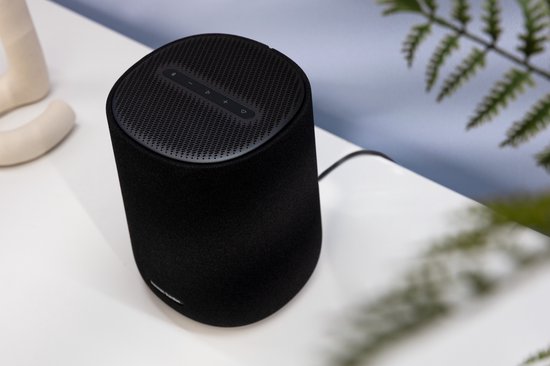 Zwarte Harman Kardon speaker met touchknoppen bovenop, op een witte ondergrond.