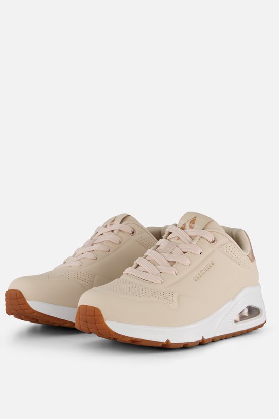 Crème Skechers UNO sneakers met roze veters, gouden accenten en een witte zool.
