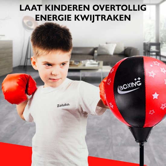 Jongen met rode bokshandschoenen slaat op een rode en zwarte boksbal met sterren.