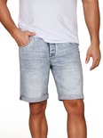 Man in een lichtblauwe, verwassen korte spijkerbroek met omgeslagen pijpen, gecombineerd met een wit T-shirt.