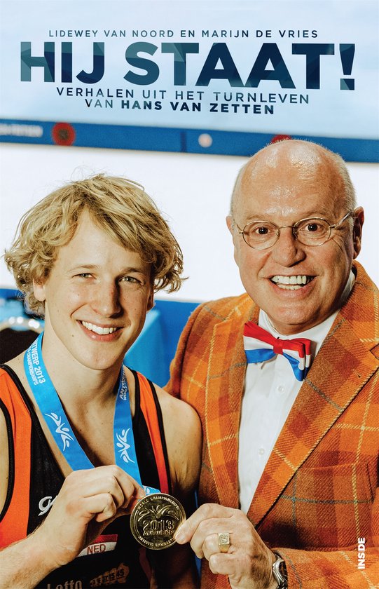 Twee mannen, een jonge turner met medaille en een oudere man met strikje en colbert, met de titel 'Hij staat!'.
