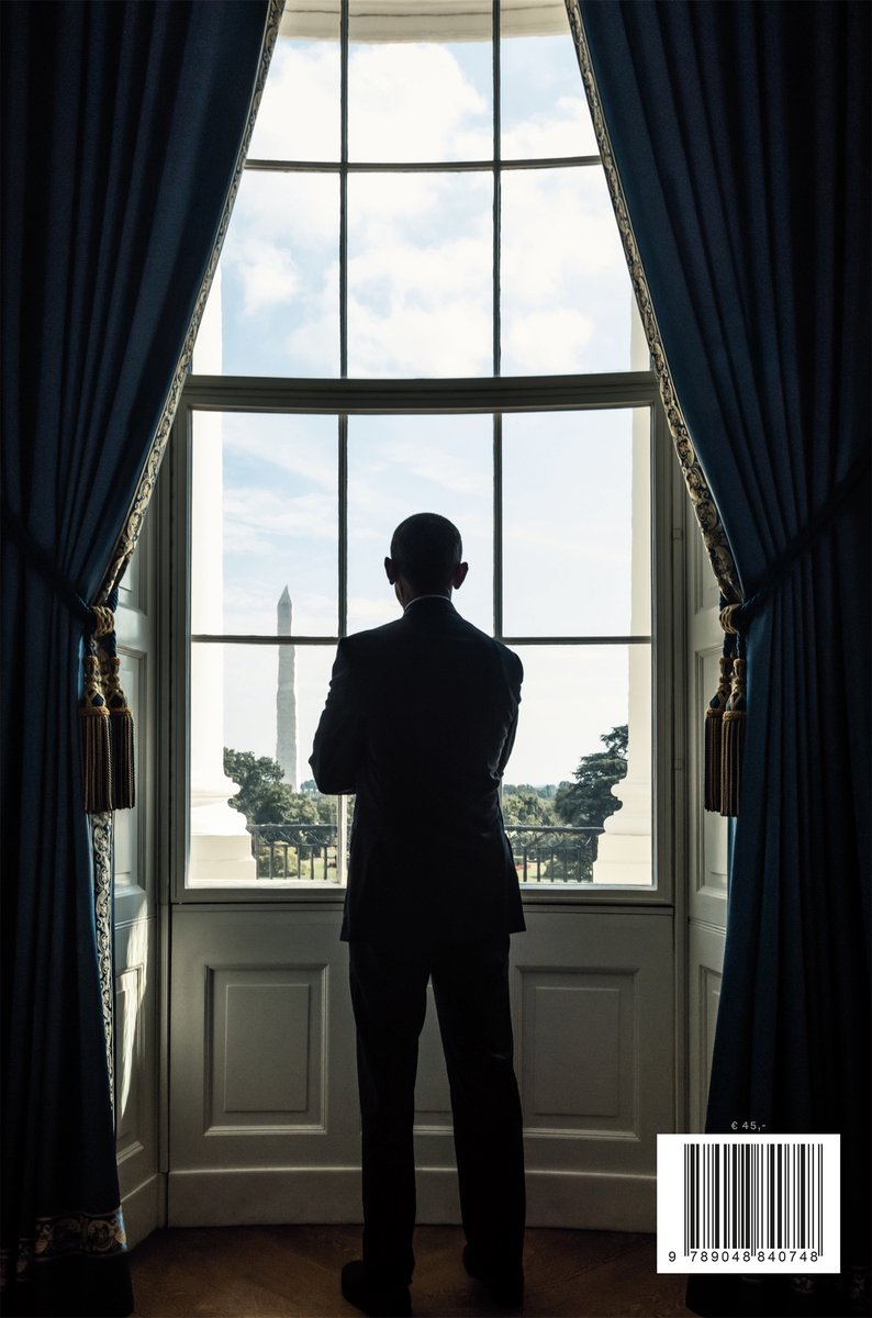 Silhouet van een man in pak, kijkend naar het Washington Monument door een raam, geflankeerd door blauwe gordijnen.