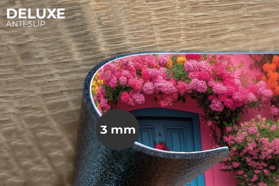 Gros plan du bord d'un set de table imprimé d'une maison rose, d'une porte bleue et de fleurs.