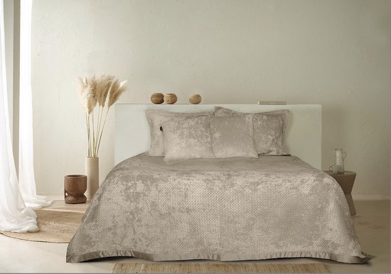 Gedrapeerde bronskleurige spreien met gedetailleerd patroon op een bed.