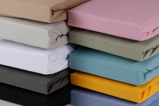 Pile de draps-housses de différentes couleurs: taupe, beige, blanc, gris, noir, rose, vert passé, bleu pétrole, jaune et bleu.