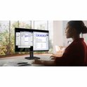 Vrouw met bril gebruikt een zwarte Philips monitor in een lichte kantoorruimte.