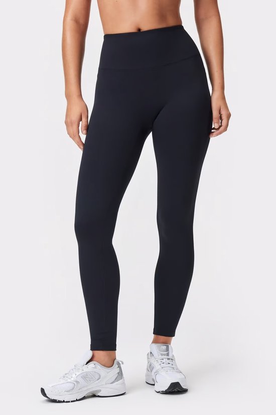 Model draagt een zwarte, nauwsluitende legging met hoge taille.