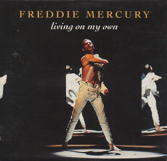 Freddie Mercury in witte broek met bretels en wit hemd, staand op een podium.