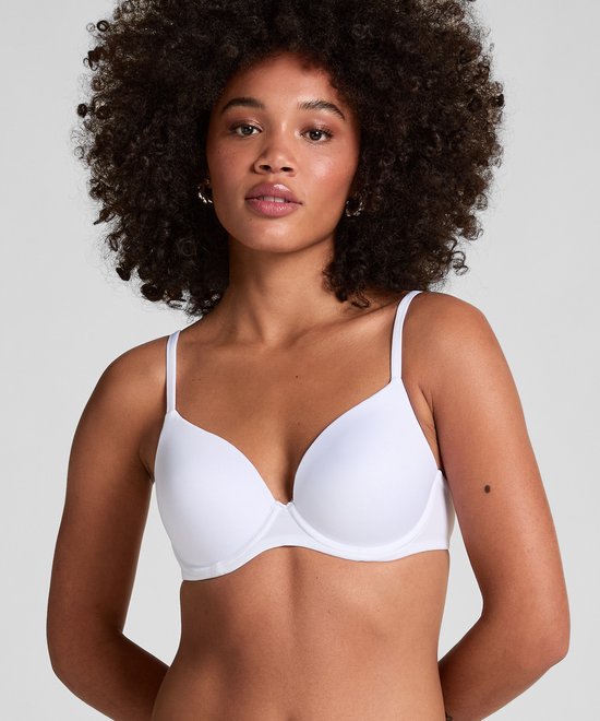 Model draagt een witte, voorgevormde beha met verstelbare bandjes. Ze heeft krullend haar en draagt gouden oorbellen.
