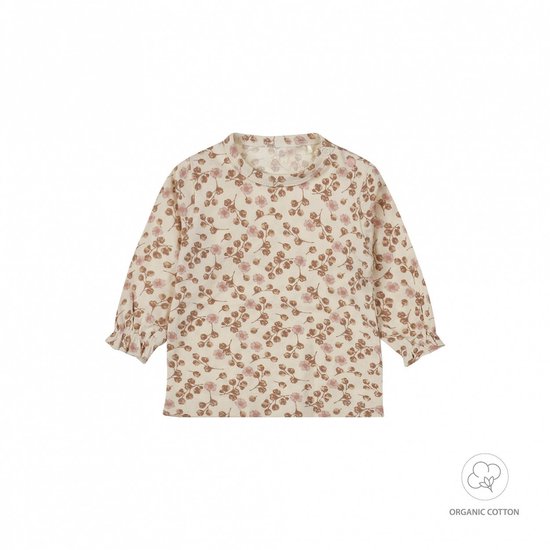 Baby ligt op haar rug, draagt een bloemenprint romper en een roze vest. Ze heeft blauwe ogen en een roze hoofdband met strik.
