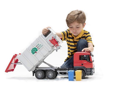 Jongen speelt met rode vuilniswagen met witte laadbak, voorzien van de tekst 'REUSE REDUCE RECYCLE'.