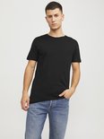 Man met de hand in de zak draagt een zwart T-shirt en een spijkerbroek.
