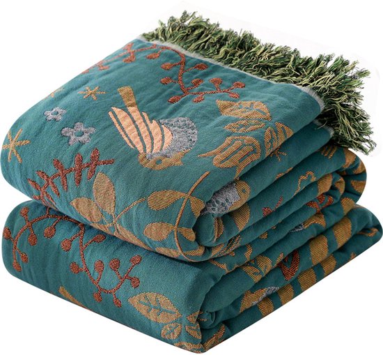Groene deken met vogel- en bloemenprint en groene franjes.