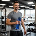 Blauwe waterfles met tijdmarkeringen, gehouden door een man in een sportschool.