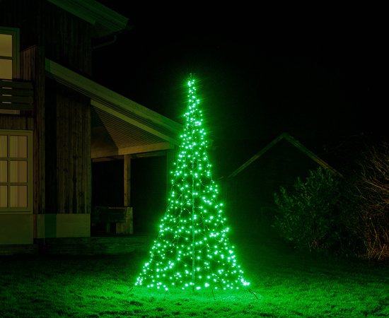 Een met groene ledlampjes versierde kerstboom voor een huis.