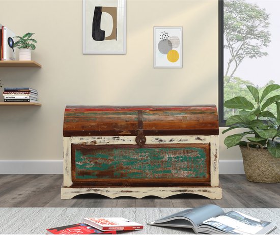 Gebogen houten kist met crème, rood en groen verweerde verf in een woonkamer.