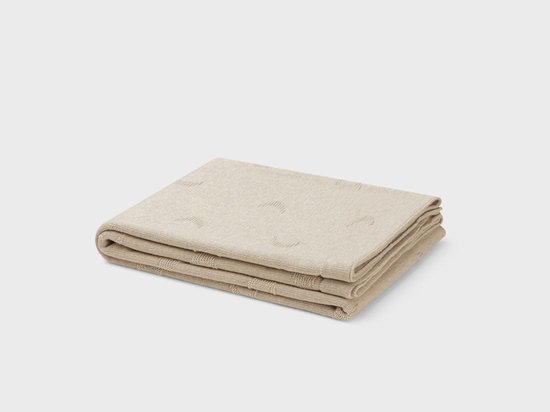 Een beige babydeken gevouwen met een subtiel ingeweven maanpatroon.