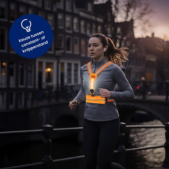 Vrouw rent 's avonds met oranje hardloopvest met witte, knipperende verlichting en oortjes.