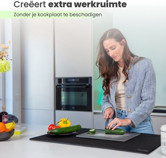 Een vrouw snijdt komkommer op een zwarte inductie beschermer. Tekst: 'Creëert extra werkruimte'.