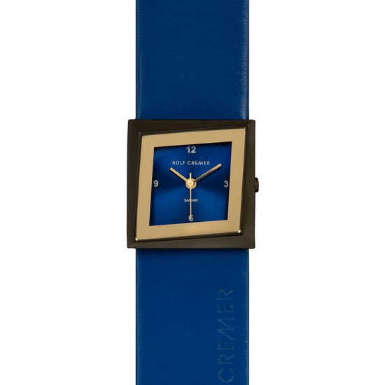 Blauw lederen horloge met vierkant gouden frame en blauwe wijzerplaat, merknaam 'ROLF CREMER' op band.