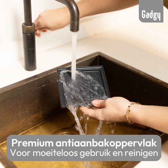 Een grijze grillplaat wordt schoongemaakt onder stromend water in een gootsteen.