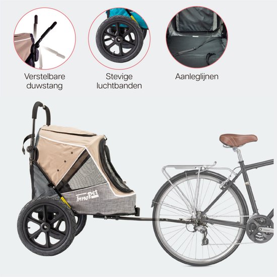 Beige hondenbuggy met grote luchtbanden, gekoppeld aan een fiets. Verstelbare duwstang en aanleglijnen.