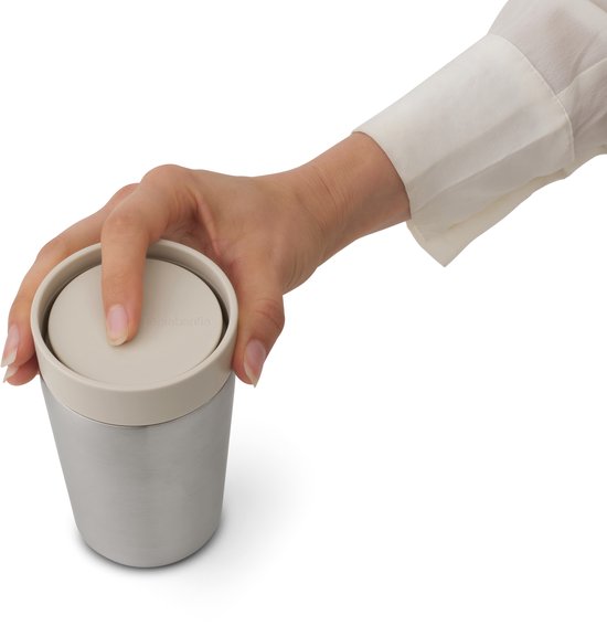 Vinger duwt op het zandkleurige deksel van een zilverkleurige thermosbeker.