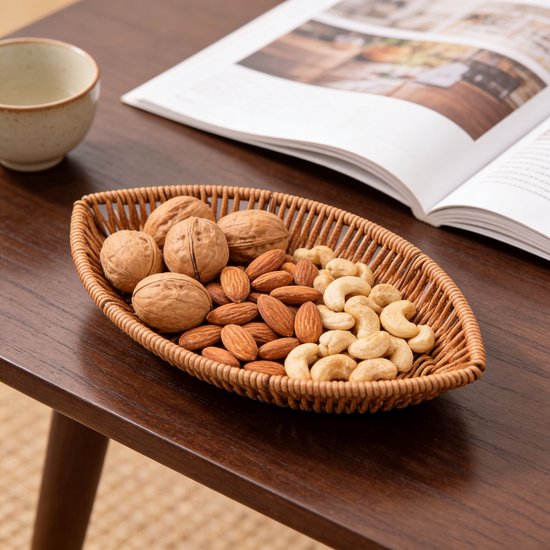 Bruine bladvormige mand van imitatie rotan, gevuld met noten op een houten tafel met een boek.