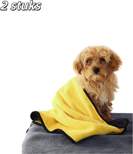 Een kleine, bruine hond zit, half bedekt met een gele en grijze handdoek.