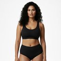 Zwarte naadloze beha met hoge slip, gezien vanaf de voorkant. Model met donker, golvend haar.