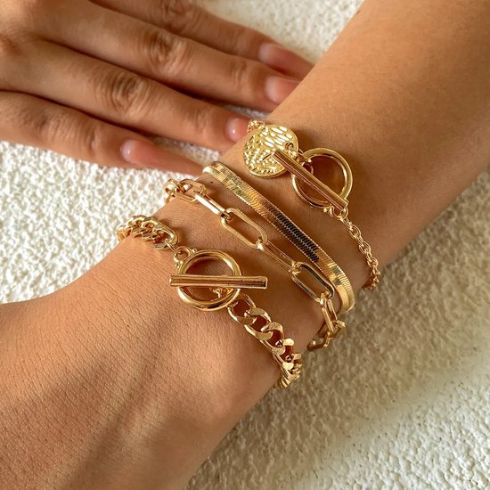 Vier gouden schakelarmbanden met toggle-sluitingen, gedragen op een pols.