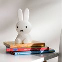 Onderkant van een wit Miffy-lampje met gele batterijdeksel en knoppen.