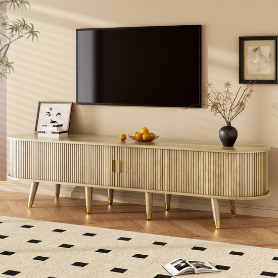 Tv-meubel met verticale ribbeldeuren, gouden handgrepen en schuine houten poten met gouden doppen.