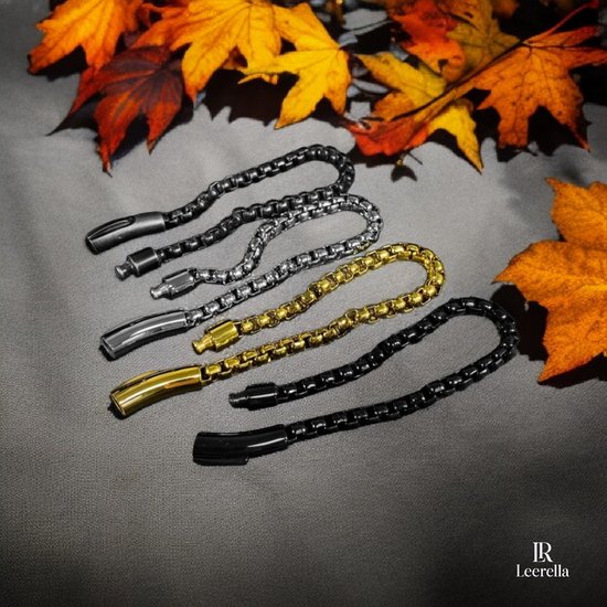 Zilverkleurige, goudkleurige en zwarte schakelarmbanden met karabijnsluitingen, tussen herfstbladeren.