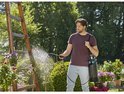 Man met donkergrijze GARDENA drukspuit met blauwe details op de schouder, sproeit planten.