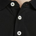 Detail van de kraag en knopen van een zwarte polo met 'JACK&JONES' op de knopen.