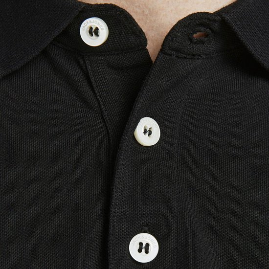 Detail van de kraag en knopen van een zwarte polo met 'JACK&JONES' op de knopen.