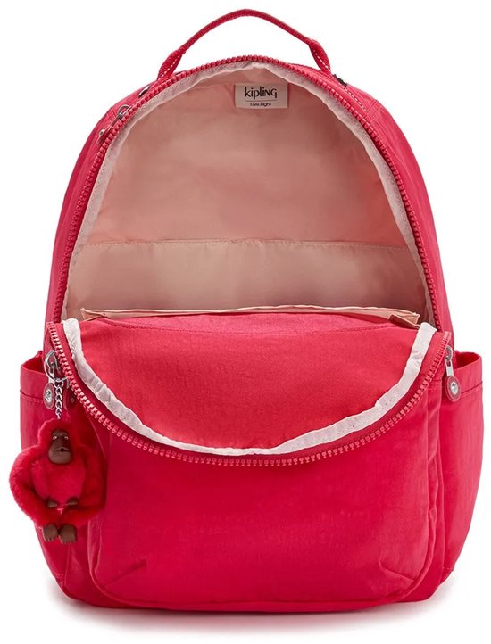 Sac à dos Kipling rouge ouvert avec doublure rose, des tons beiges et un porte-clés singe rouge.