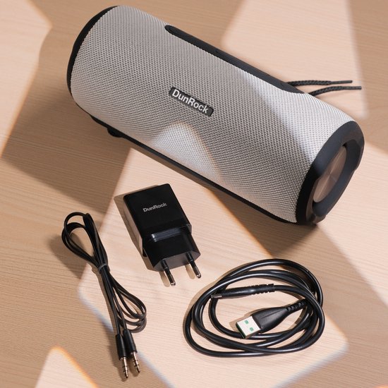 DunRock bluetooth speaker in grijs met zwarte details, met oplader en kabels.