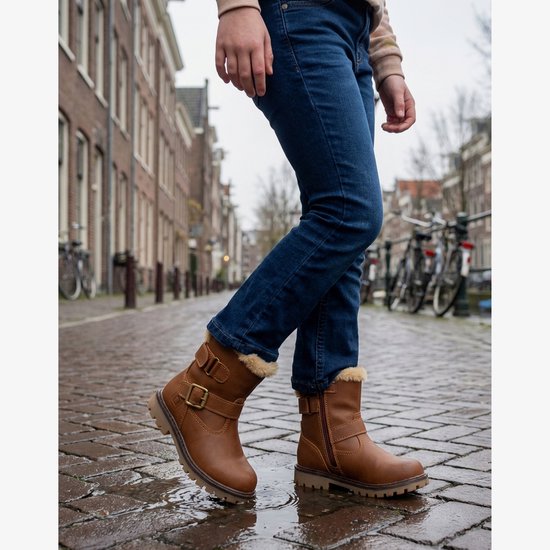 Meisje draagt bruine biker boots met jeans in een stadse omgeving.