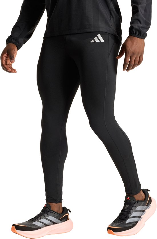 Model in zwarte sportlegging met zilverkleurig Adidas-logo op de linkerheup, gedragen met sportshirt en schoenen.