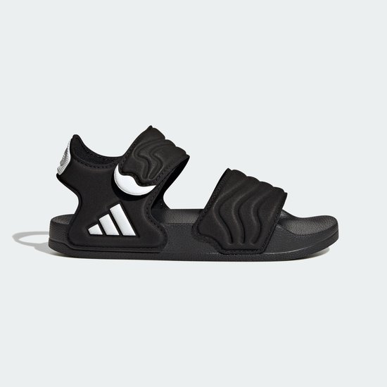Zwarte Adidas Adilette kindersandaal met golvend patroon, klittenband en drievoudig wit logo.