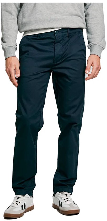 Donkerblauwe chino gedragen met grijze trui en witte sneakers.