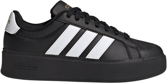 Zwarte damessneaker met dikke zool, witte Adidas-strepen op de zijkant en gouden details.
